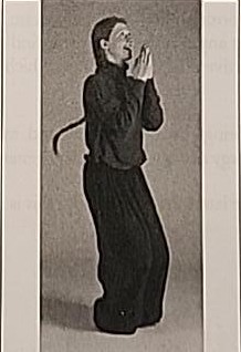 Photograph of a practitioner performing the moving Heh, exhaling with arms outstretched after the jump.