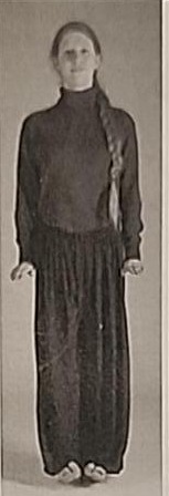 Photograph of a practitioner performing the Nun posture from the front, balancing on the heels with hands bent upward.