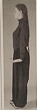 Photograph of a practitioner performing the Nun posture from the side, balancing on the heels with toes raised.