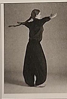 Photograph of a practitioner performing the moving Yud, mid-turn with arms extended.