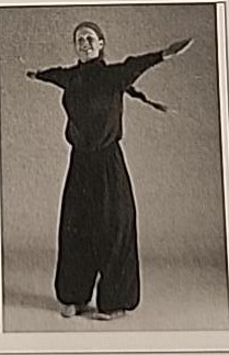 Photograph of a practitioner performing the moving Yud from another angle, mid-turn with arms extended.